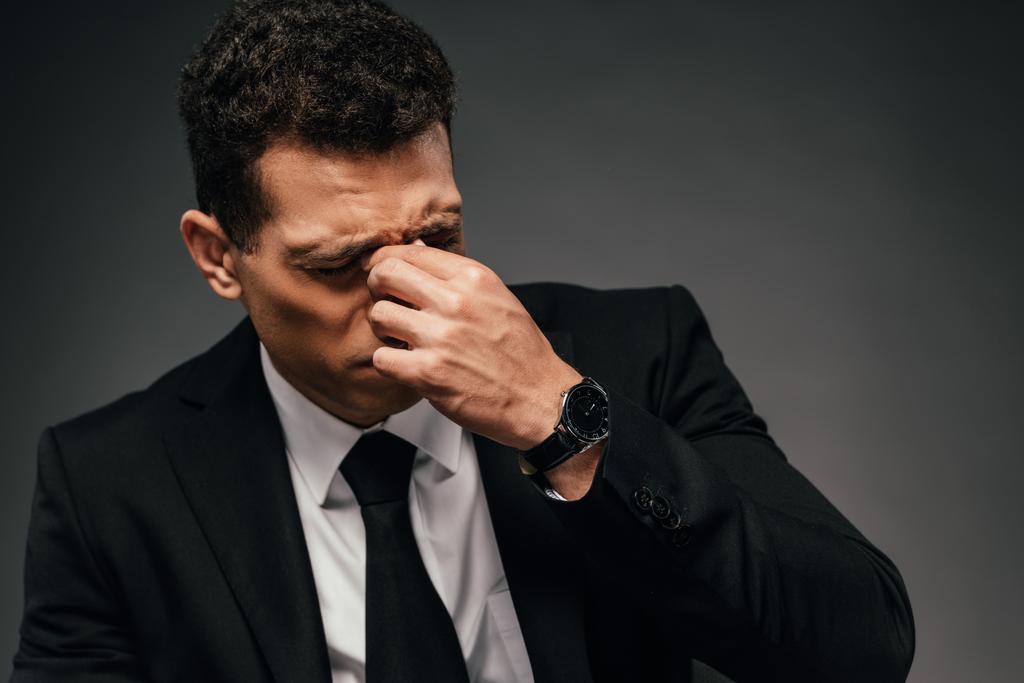 tired african american businessman in wristwatch rubbing his eyes on dark background - Photo, Image
