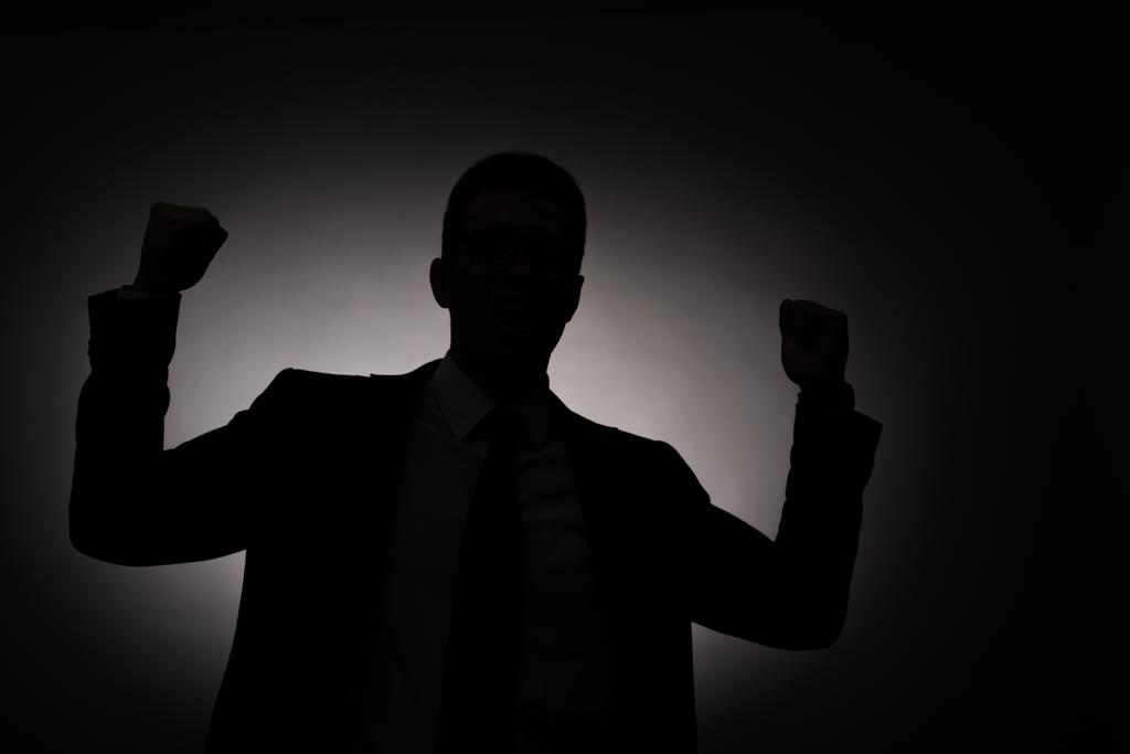 バックライトでイエスジェスチャーを示すビジネスマンの黒いシルエット - 写真・画像