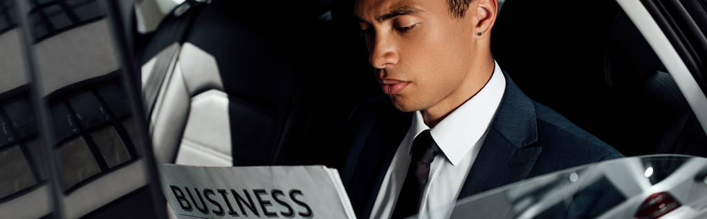 панорамный снимок африканского бизнесмена, читающего деловую газету в автомобиле
 - Фото, изображение