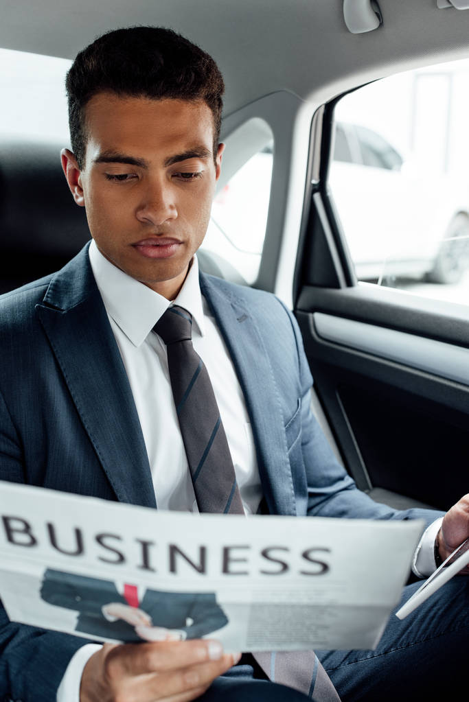 σίγουρος Αφρικανός Αμερικανός επιχειρηματίας διαβάζοντας επιχειρηματική εφημερίδα στο αυτοκίνητο - Φωτογραφία, εικόνα