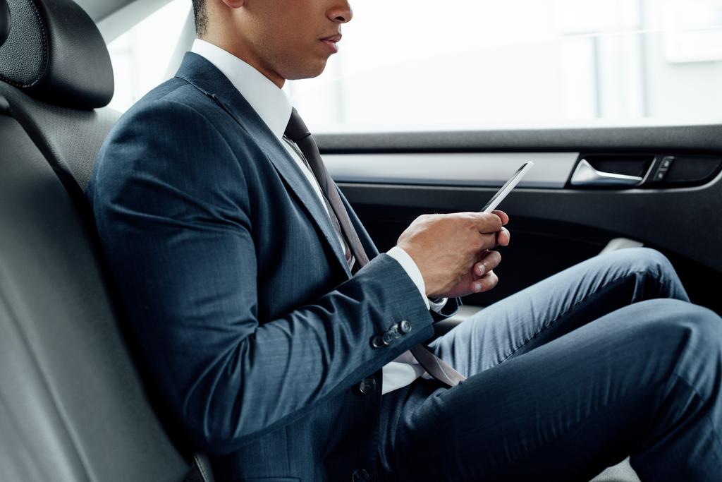 vue partielle d'un homme d'affaires afro-américain utilisant un smartphone en voiture
 - Photo, image