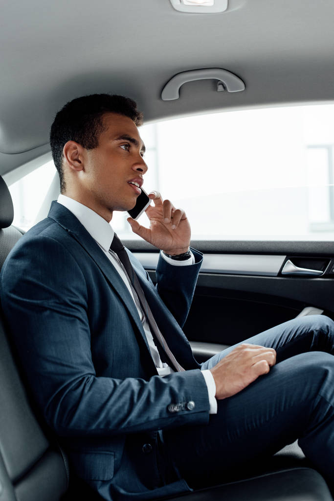 Afrikanisch-amerikanischer Geschäftsmann im Anzug spricht im Auto auf Smartphone - Foto, Bild