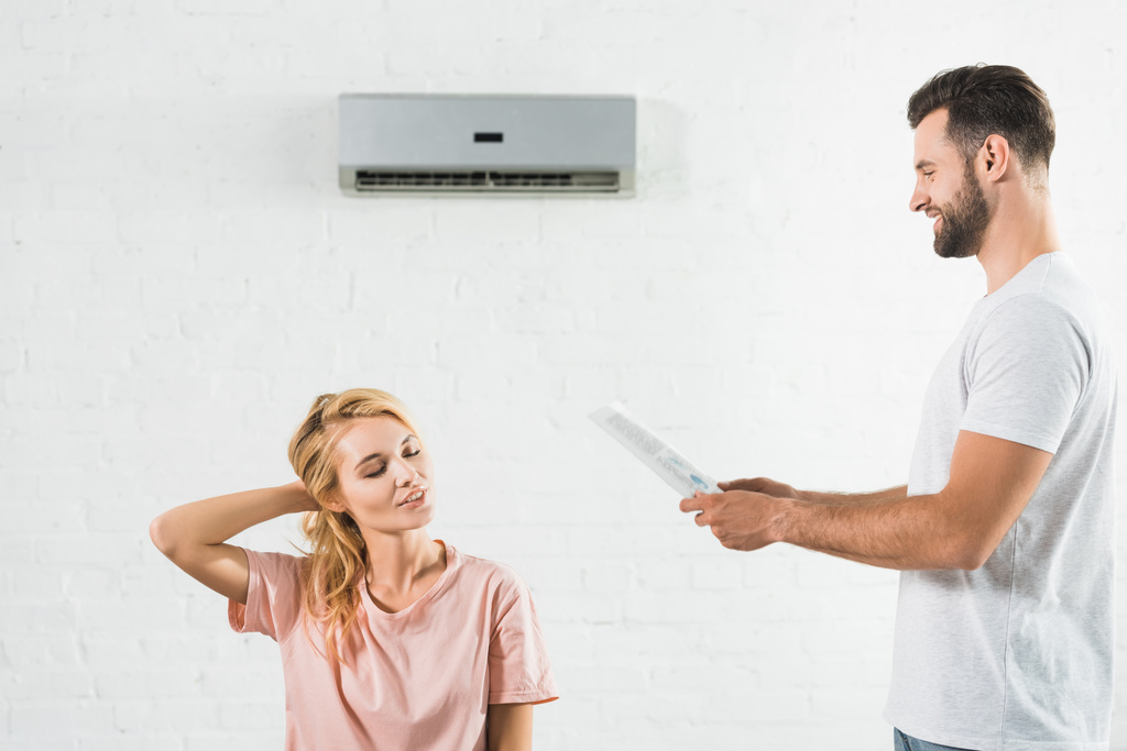 coppia che soffre di calore sotto condizionatore d'aria a casa
 - Foto, immagini