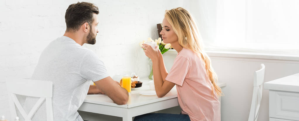 plano panorámico de hermosa pareja desayunando en la mesa de la cocina por la mañana
 - Foto, Imagen