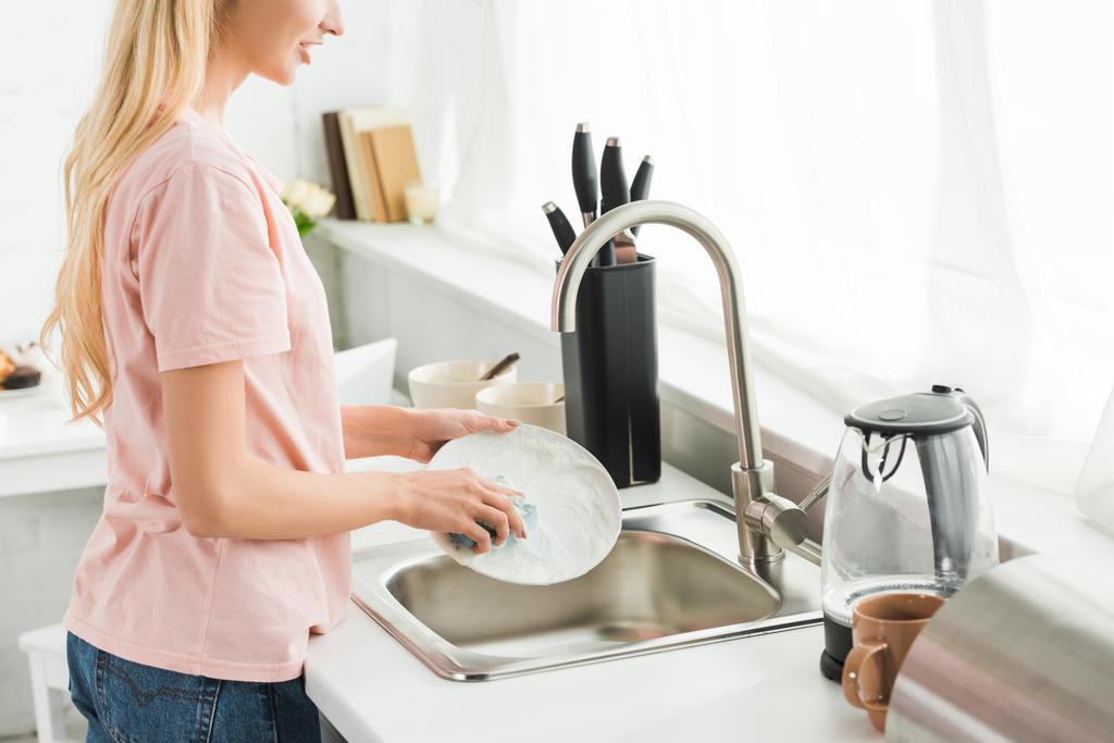 朝の台所で皿洗いをする女性のトリミングビュー - 写真・画像