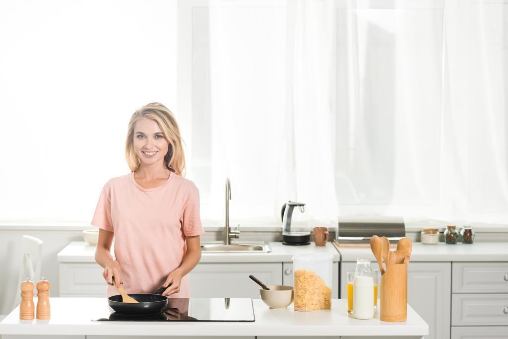 красива жінка готує з сковородою і шпателем на кухні вранці
 - Фото, зображення
