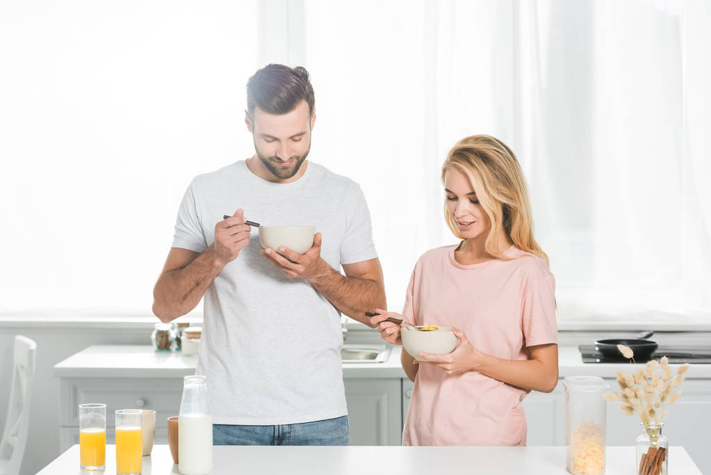 счастливая пара ест хлопья во время завтрака на кухне
 - Фото, изображение