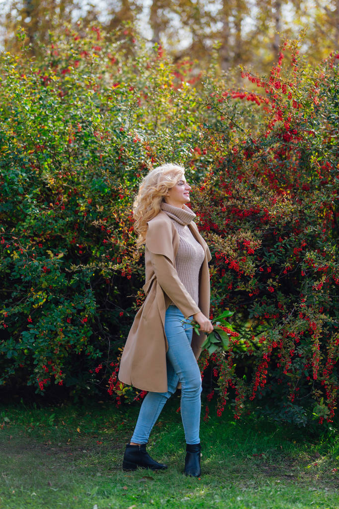 Gyönyörű elegáns nő áll a jövő mahónia bokor őszi parkban - Fotó, kép