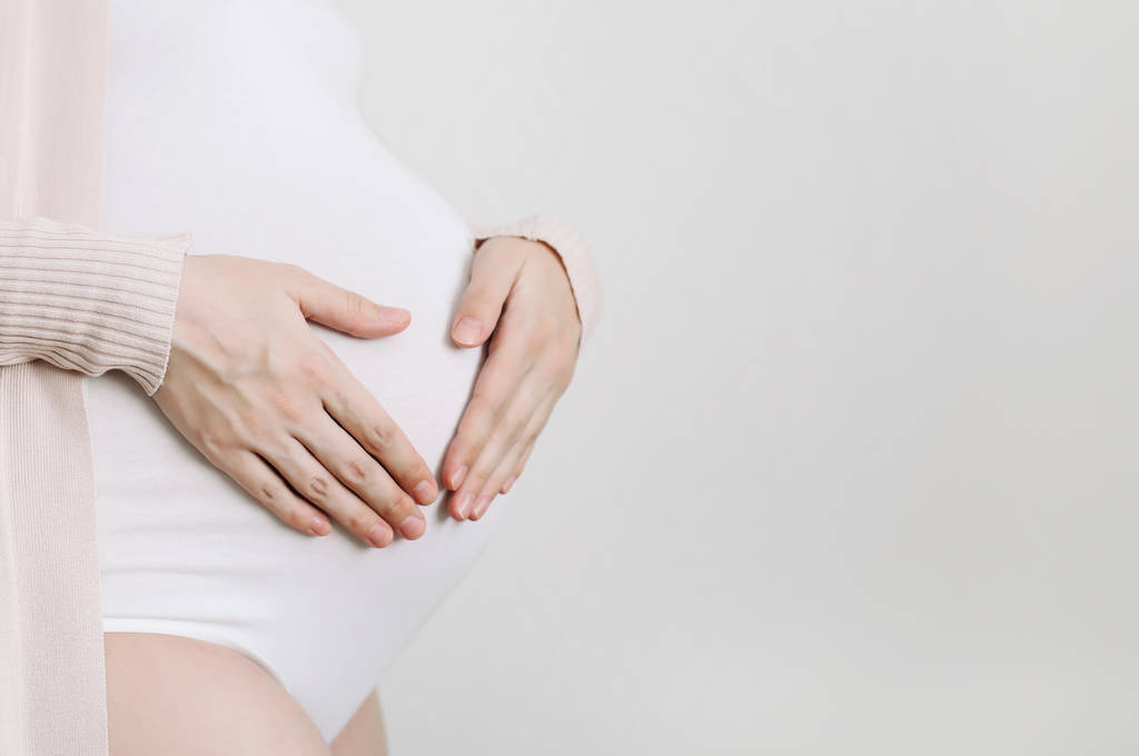 Pancia di donna incinta, forma di cuore in gravidanza, segno d'amore. Il concetto di maternità. Doccia per bambini
  - Foto, immagini