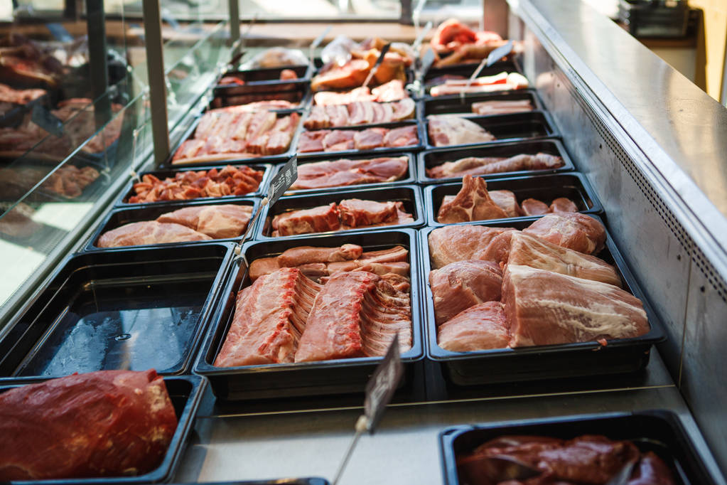 Viande crue dans des plateaux à la fenêtre d'une boucherie. Le vendeur expose la viande dans des plateaux noirs
 - Photo, image