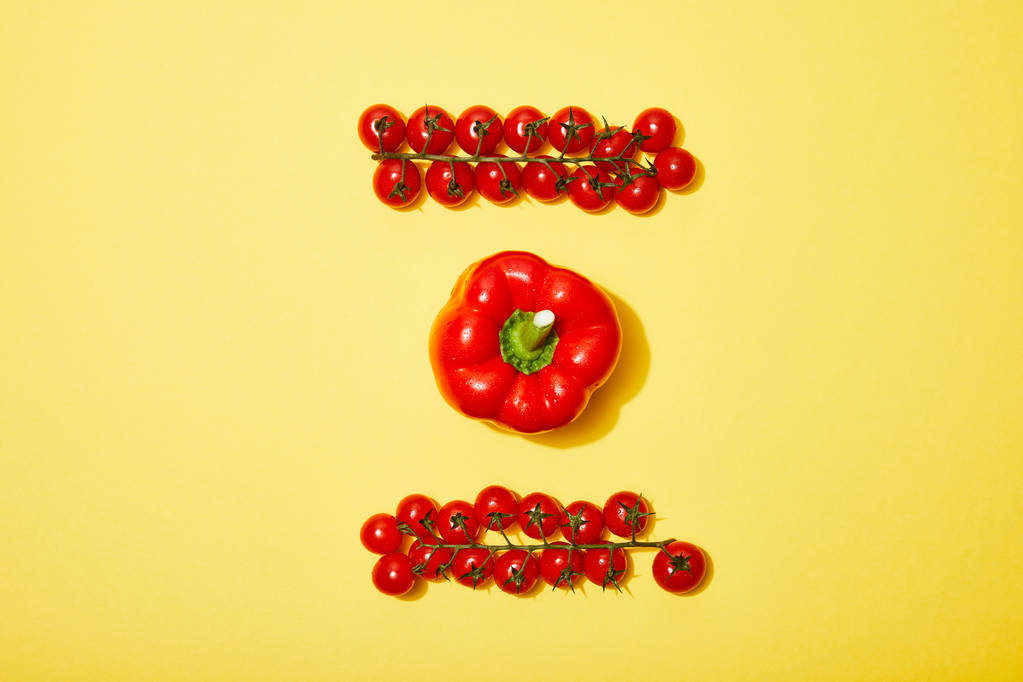 platte lay met rode cherry tomaten en paprika op gele achtergrond - Foto, afbeelding