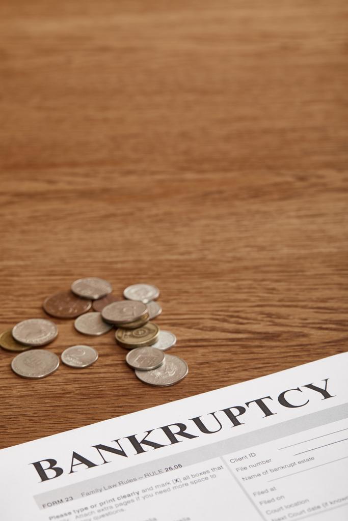 форма банкротства и монеты на коричневом деревянном столе
 - Фото, изображение