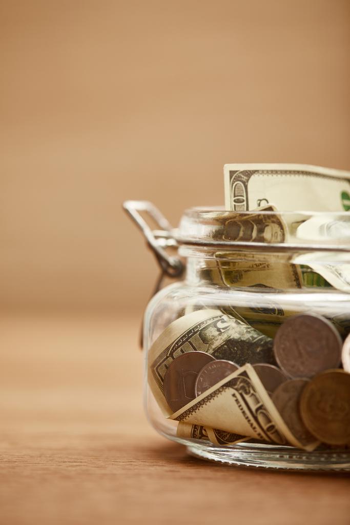 Close-up uitzicht op glazen pot met dollar bankbiljetten en-munten - Foto, afbeelding