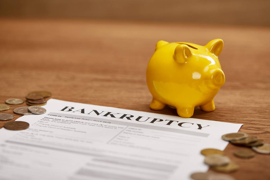 selectieve focus van faillissement vorm, munten, gele Piggy Bank op houten tafel - Foto, afbeelding