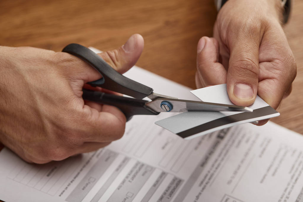 обрізаний вид бізнесмена, що ріже кредитну картку з ножицями за дерев'яним столом
  - Фото, зображення
