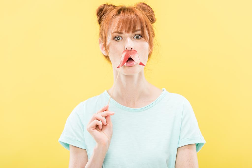 Vooraanzicht van verbaasd Redhead meisje in t-shirt Holding Toy snor - Foto, afbeelding