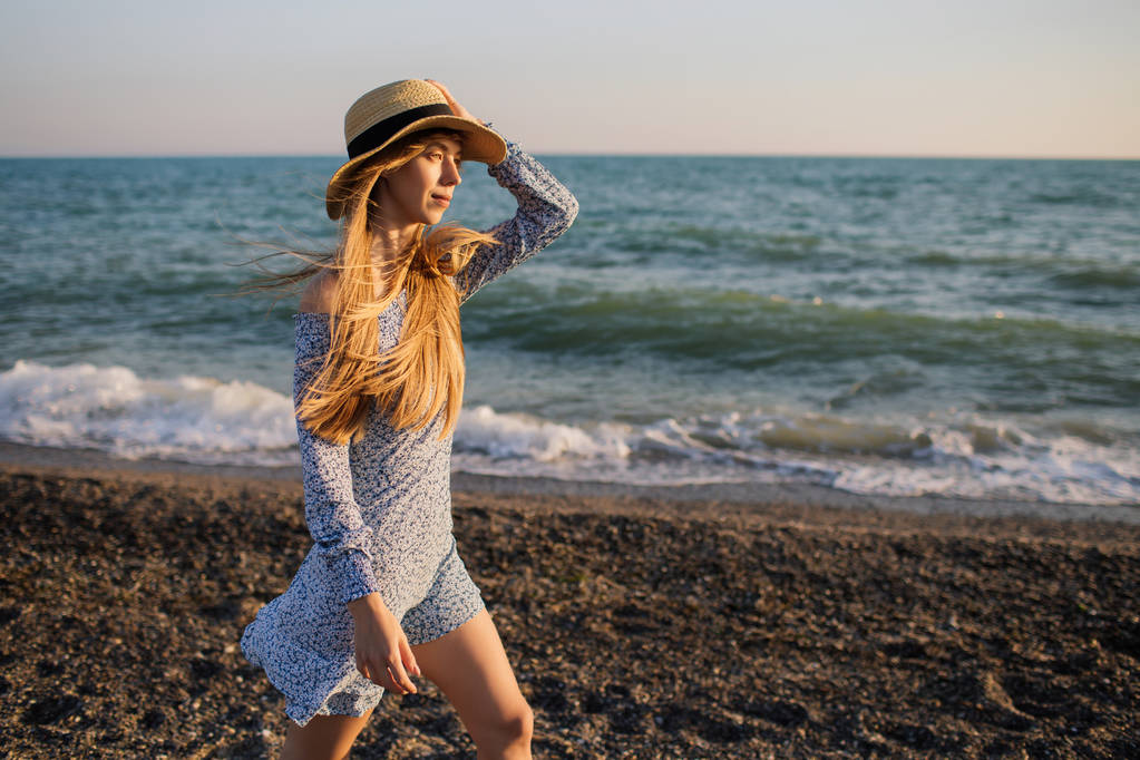 Hermosa chica en sombrero caminando por la playa
. - Foto, Imagen