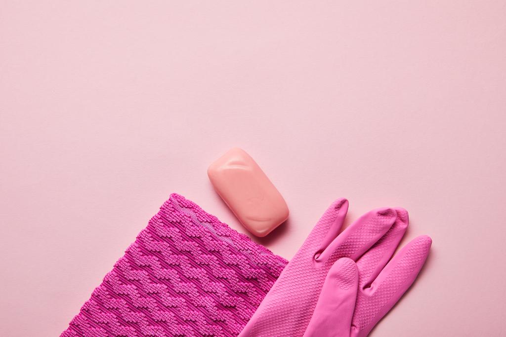 felülnézetben rózsaszín rongyot, gumi kesztyű és szappan rózsaszín háttér  - Fotó, kép