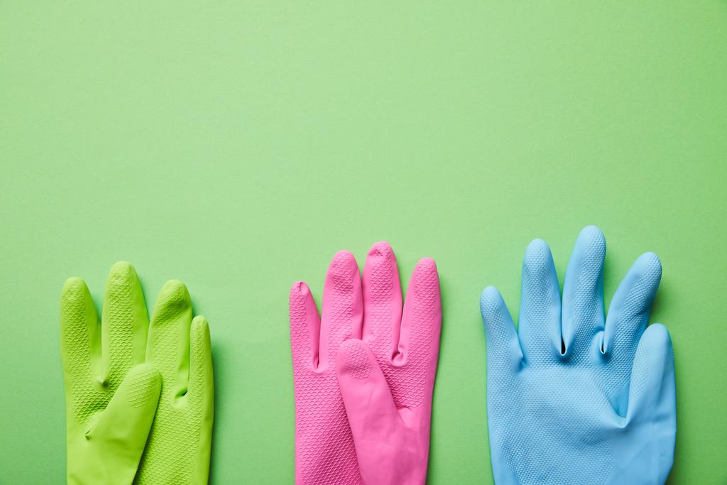 vista superior de guantes de goma brillantes y coloridos sobre fondo verde
  - Foto, Imagen