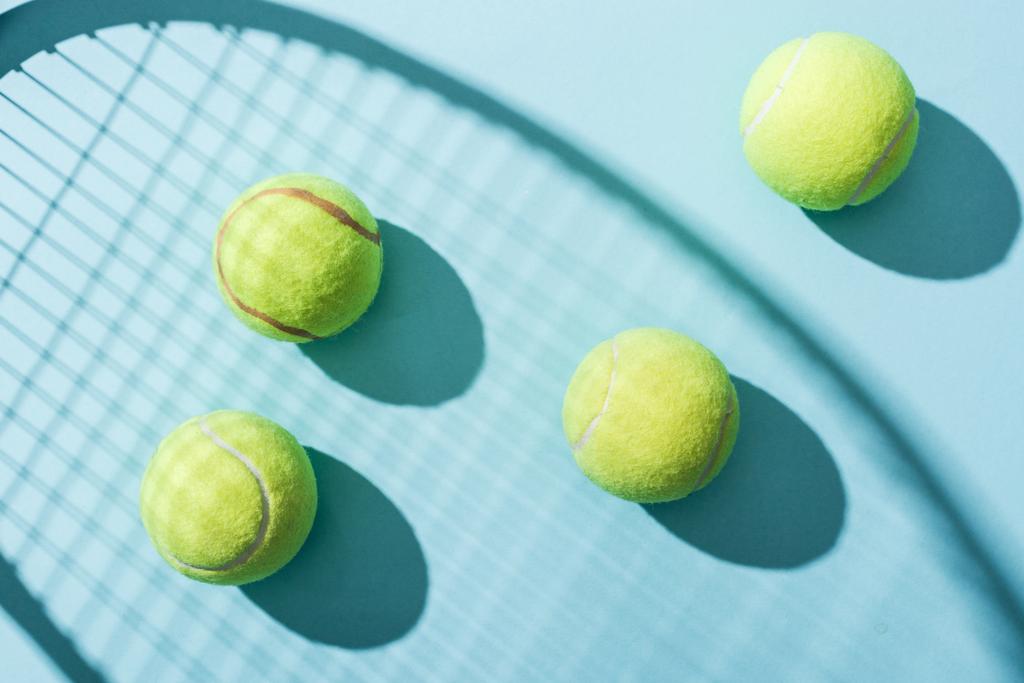 top view of tennis balls near shadow of tennis racket on blue  - Photo, Image
