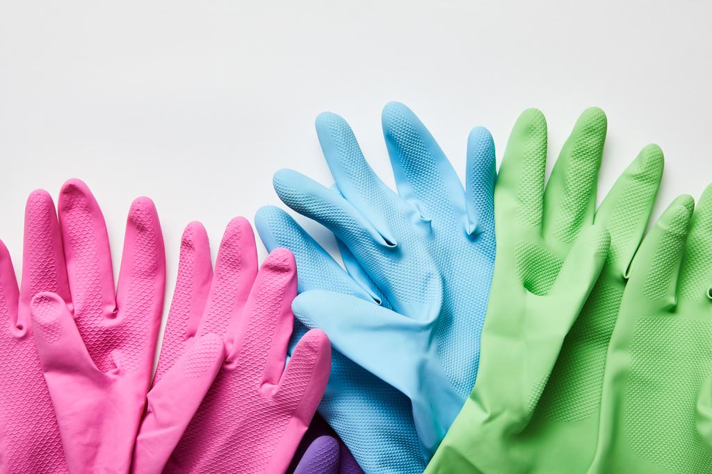 Κορυφαία θέα από ροζ, πράσινα και μπλε λαστιχένια γάντια σε γκρίζο φόντο  - Φωτογραφία, εικόνα