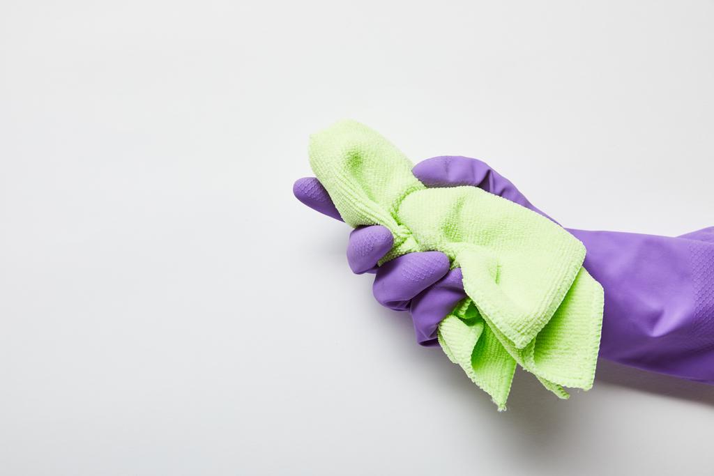 περικομμένη όψη του ανθρώπου σε μοβ ελαστικό γάντι κρατώντας πράσινο πανί  - Φωτογραφία, εικόνα