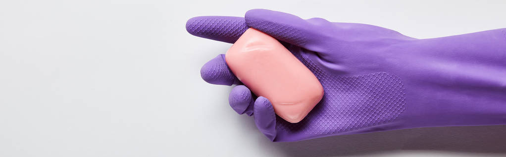 panoramiczne ujęcie człowieka w fioletowej gumowej rękawiczce trzymania różowego mydła  - Zdjęcie, obraz