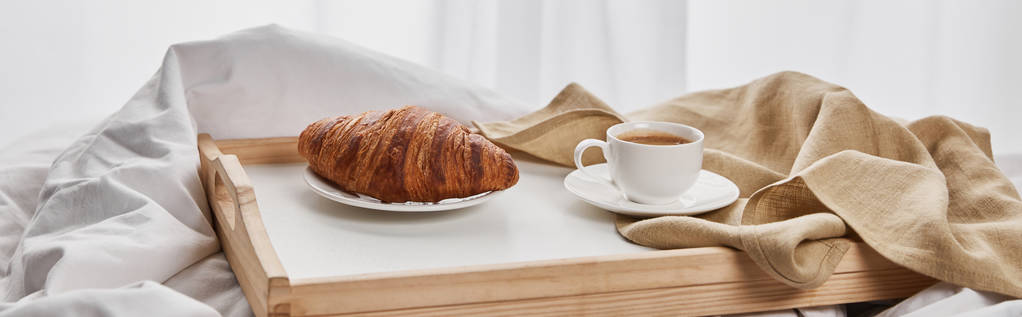 káva a croissant podávané na dřevěném tácu na bílých lůžkovnách, panoramatické výstřelu - Fotografie, Obrázek