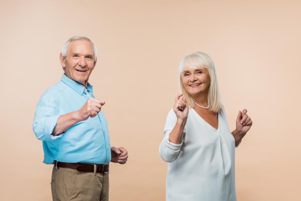 веселая старшая пара жестикулирует, улыбаясь на бежевый цвет
  - Фото, изображение