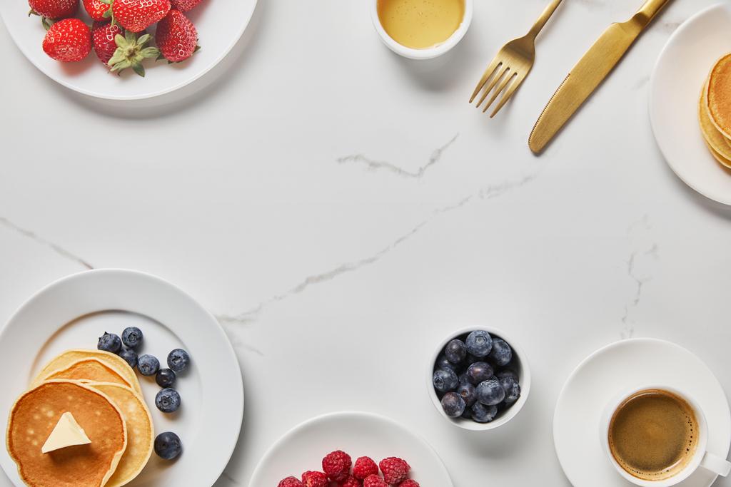 vista superior do café da manhã saboroso com panquecas, mel, diferentes tipos de bagas e xícara de café
 - Foto, Imagem