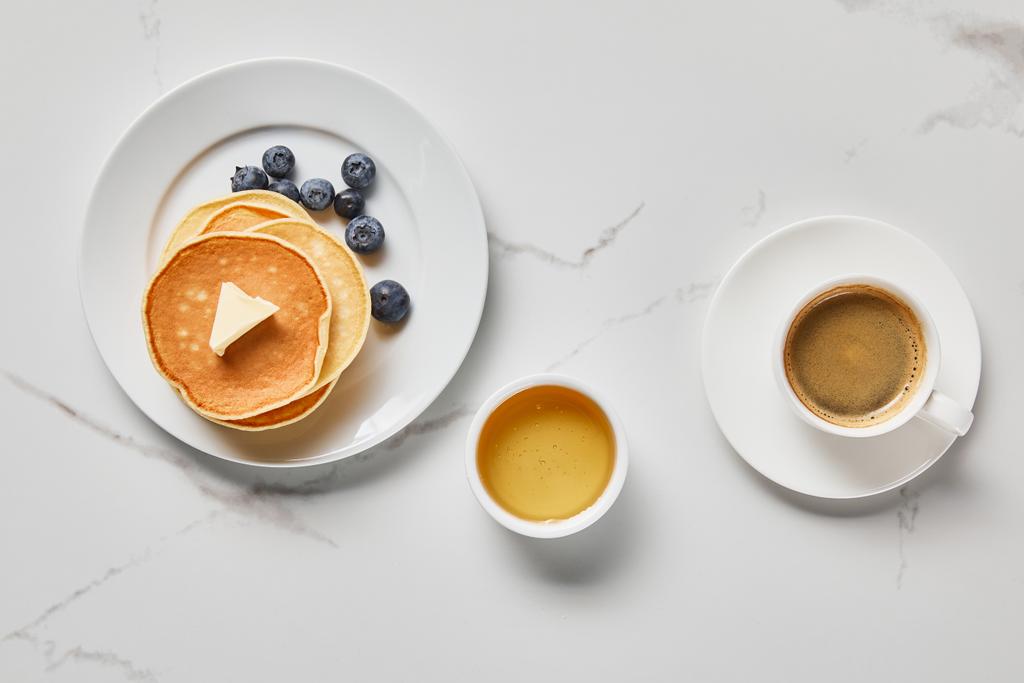 vista superior da tigela com mel, panquecas saborosas com mirtilos e xícara de café
 - Foto, Imagem