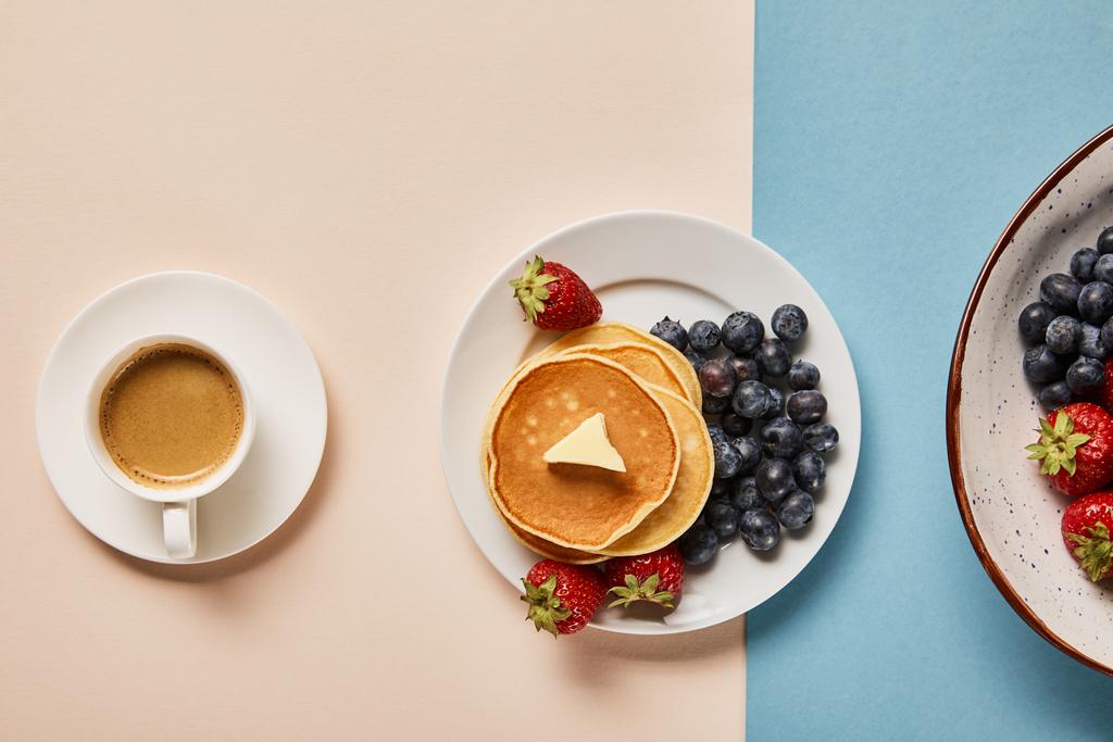 top view of pancakes with berries on plate near cup of coffee  - Photo, Image