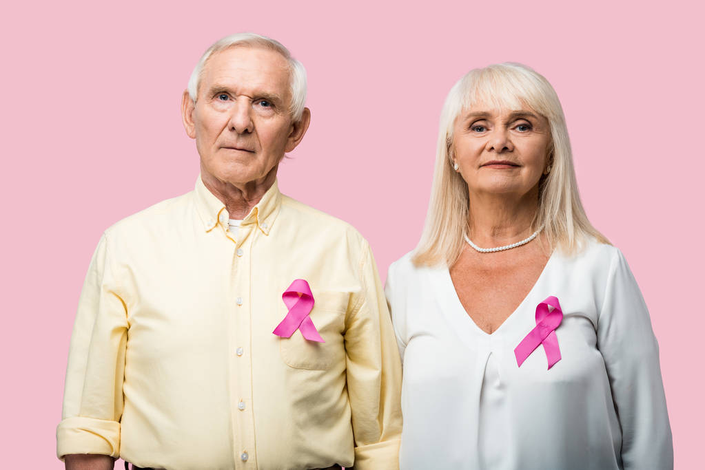 Rentnerpaar mit grauen Haaren und Schleifen als Mobbing-Bewusstsein isoliert auf rosa  - Foto, Bild