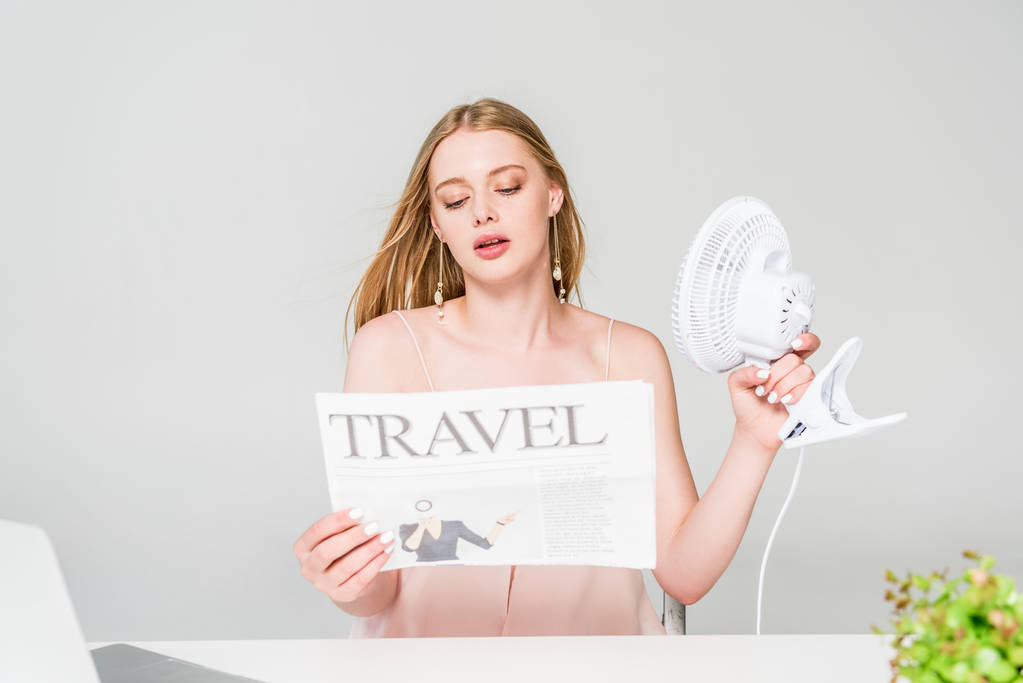 piękna młoda kobieta z wentylatorem elektrycznym i gazetą podróżną cierpiącym na ciepło na szaro - Zdjęcie, obraz