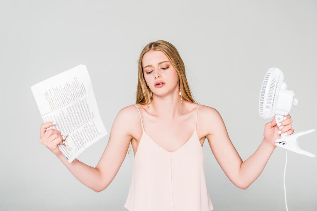 bela jovem com ventilador elétrico e jornal sofrendo de calor no cinza
 - Foto, Imagem