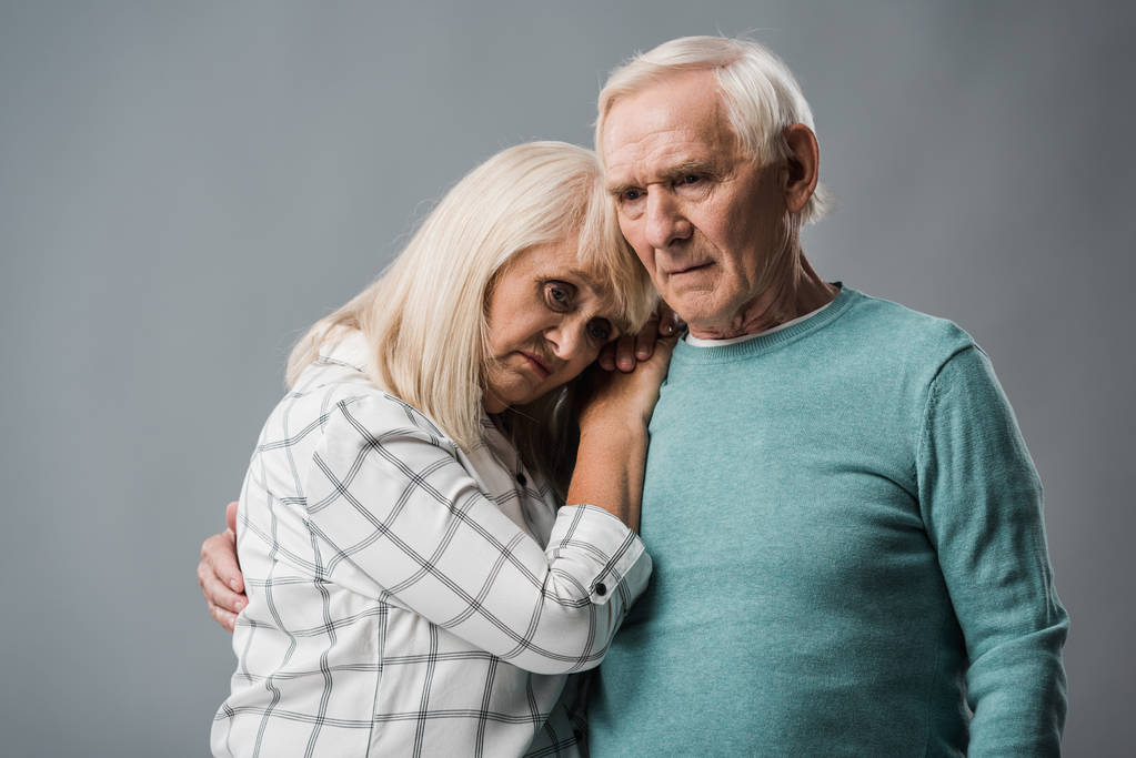αναστατωμένος συνταξιούχος άντρας αγκαλιάζει απογοητευμένος γυναίκα απομονώνεται σε γκρι  - Φωτογραφία, εικόνα