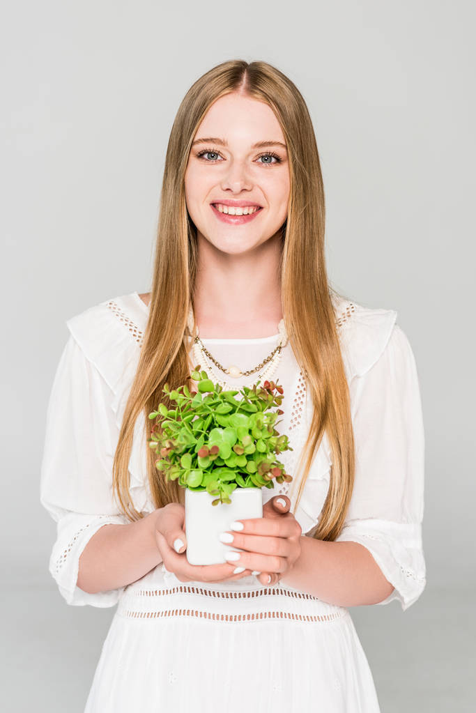 hermosa niña sosteniendo maceta con planta aislada en gris
 - Foto, Imagen