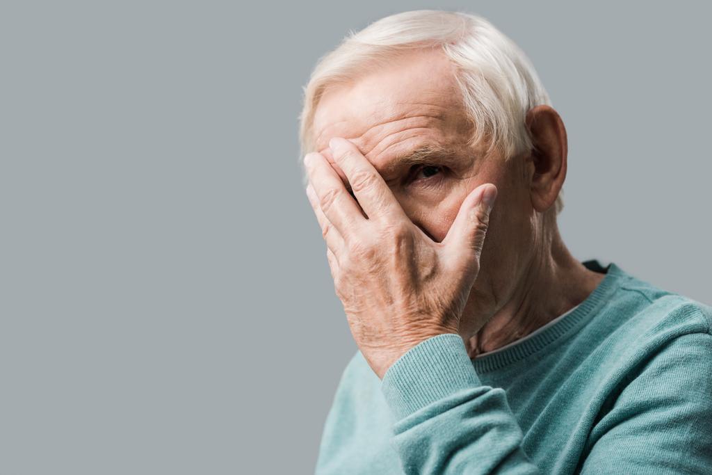 bouleversé retraité couvrant visage et regardant caméra isolé sur gris
  - Photo, image