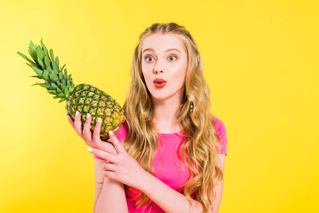 kaunis yllättynyt tyttö tilalla ananas eristetty keltainen
 - Valokuva, kuva