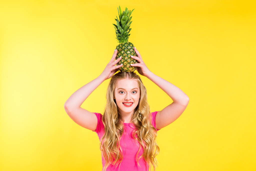 piękna dziewczyna pozowanie z ananasem na głowie izolowane na żółto - Zdjęcie, obraz