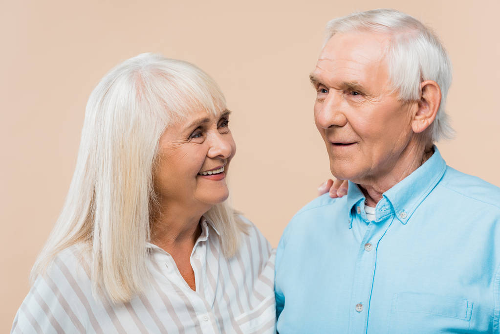 happy retired woman looking at man with grey hair isolated on beige  - Photo, Image