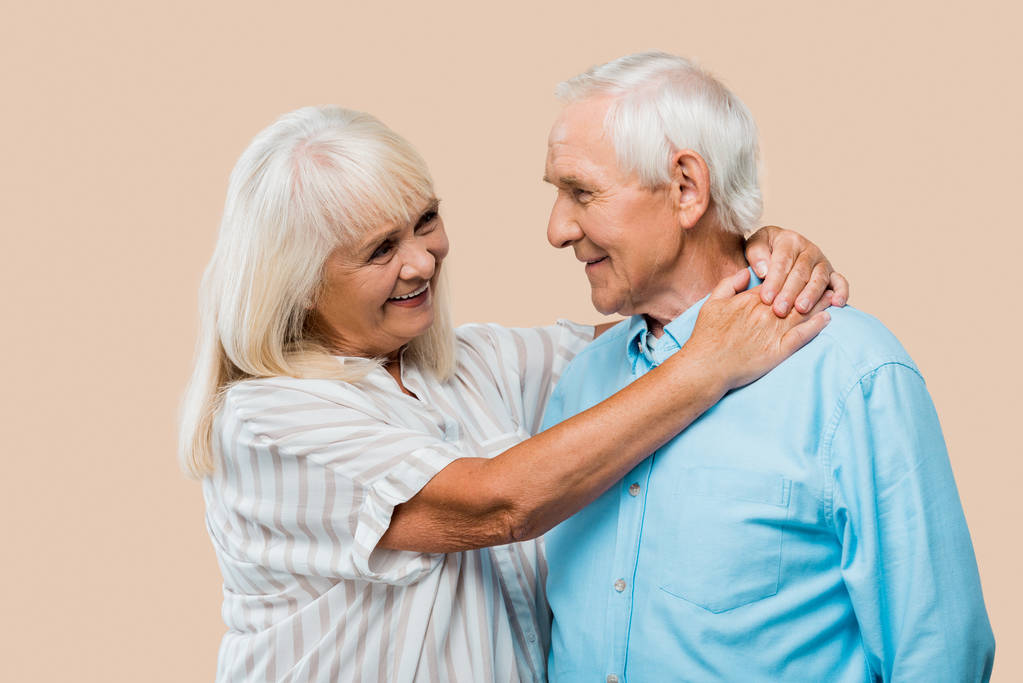 Gelukkig gepensioneerde vrouw knuffelen Senior man geïsoleerd op beige  - Foto, afbeelding