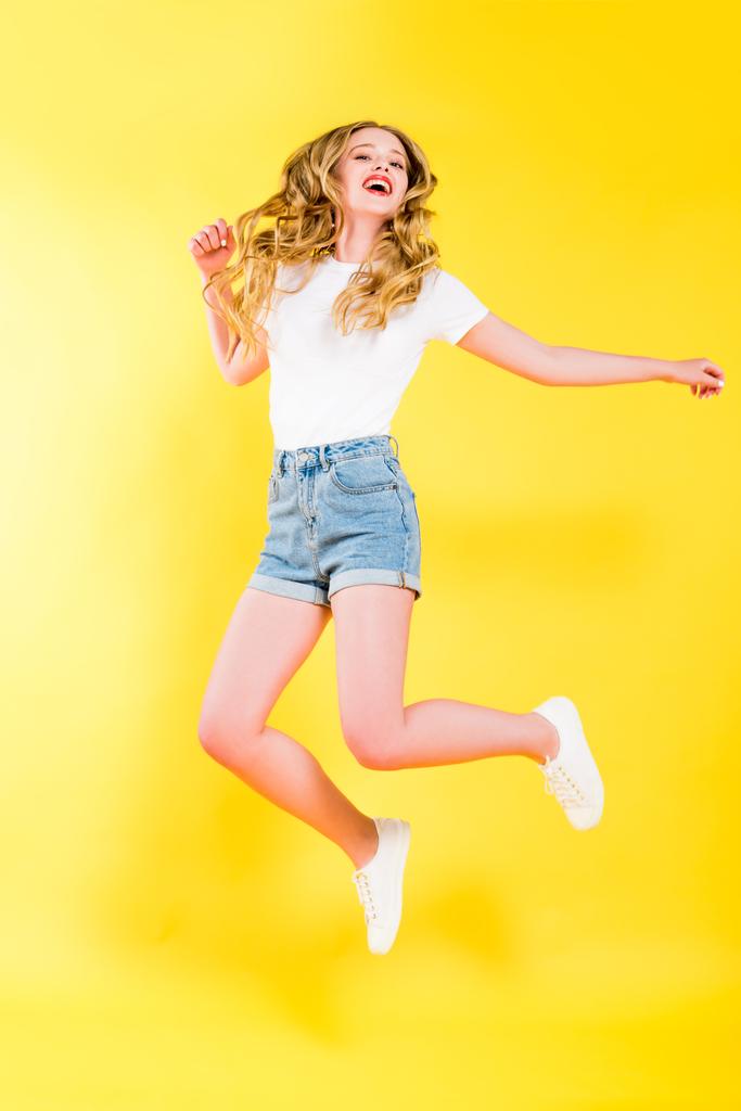 szép boldog szőke fiatal nő jumping sárga - Fotó, kép