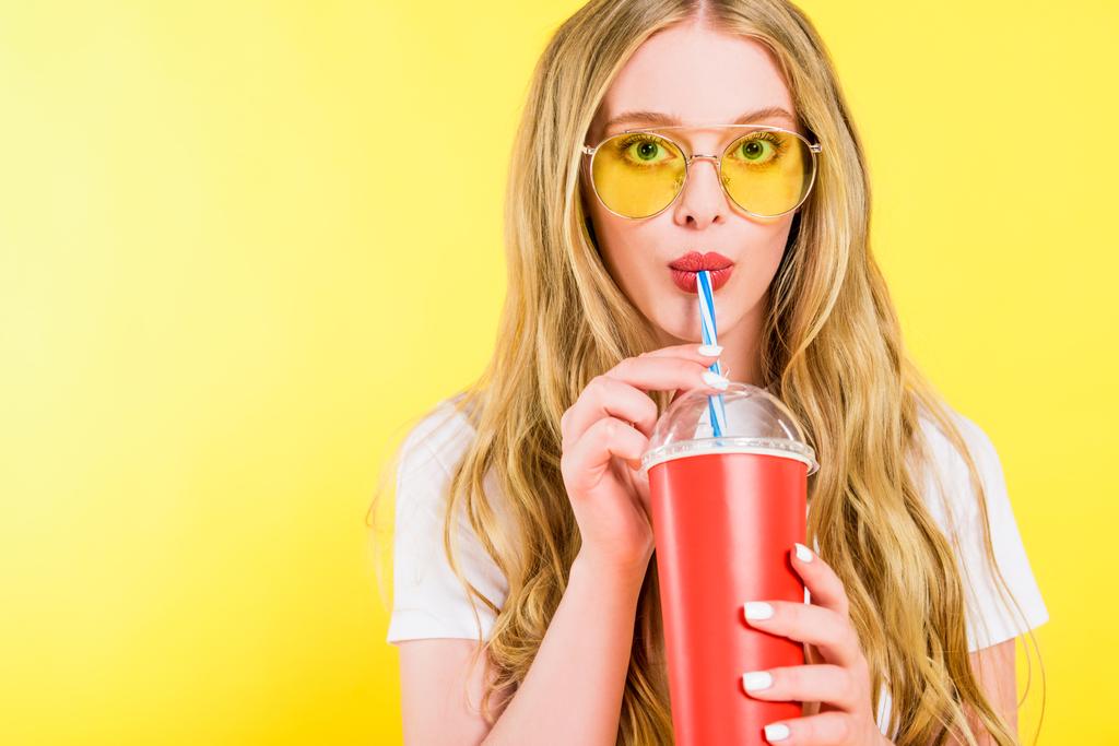 krásná dívka v brýlích s nápojem na jednorázových šálkách na žlutém  - Fotografie, Obrázek
