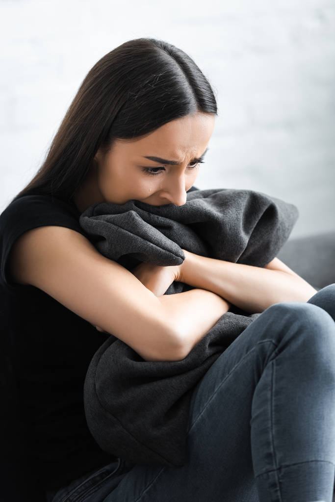 mujer joven desesperada abrazando almohada mientras sufre de depresión en casa
 - Foto, Imagen