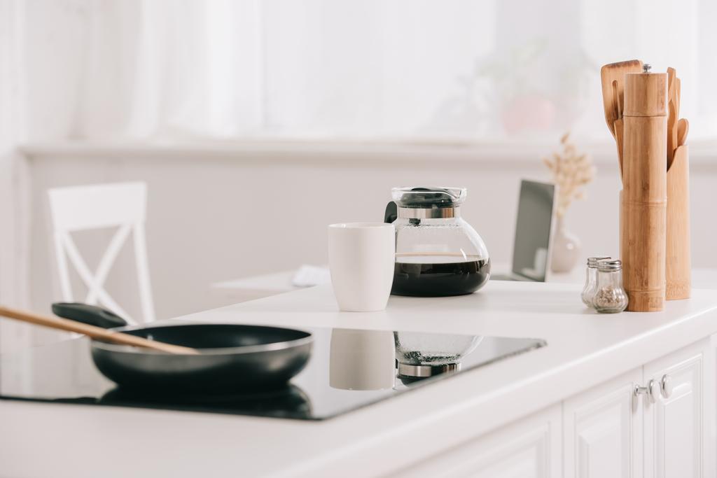 stół kuchenny z patelnią na powierzchni gotowania w pobliżu garnka do kawy i filiżanki - Zdjęcie, obraz