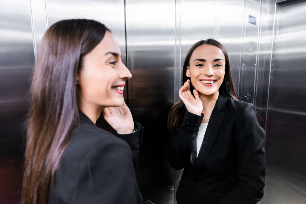 vonzó, boldog üzletasszony a liftben mosolyogva és integetett kézzel - Fotó, kép