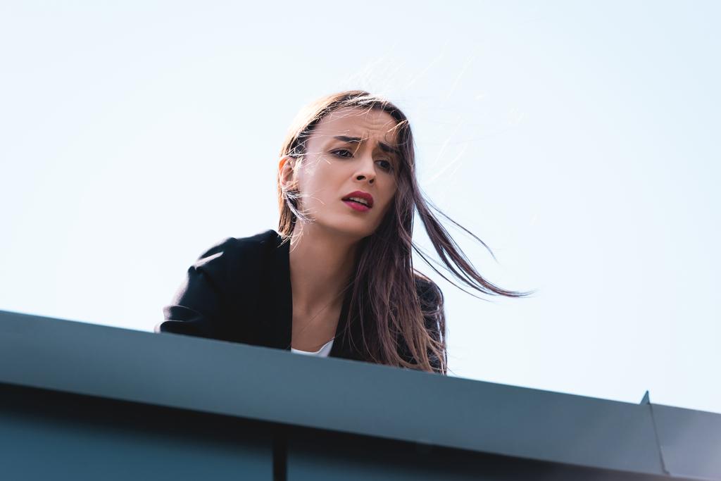 молодая деловая женщина, страдая от страха высоты, глядя с крыши
 - Фото, изображение
