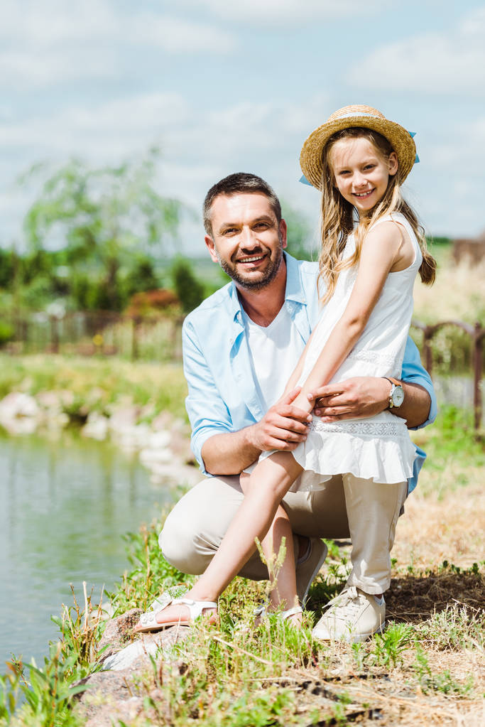 selective focus of cute kid standing near happy father and lake  - Photo, Image