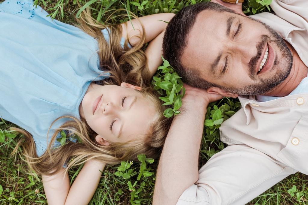 felülnézet a boldog apa és lánya feküdt a zöld fű  - Fotó, kép